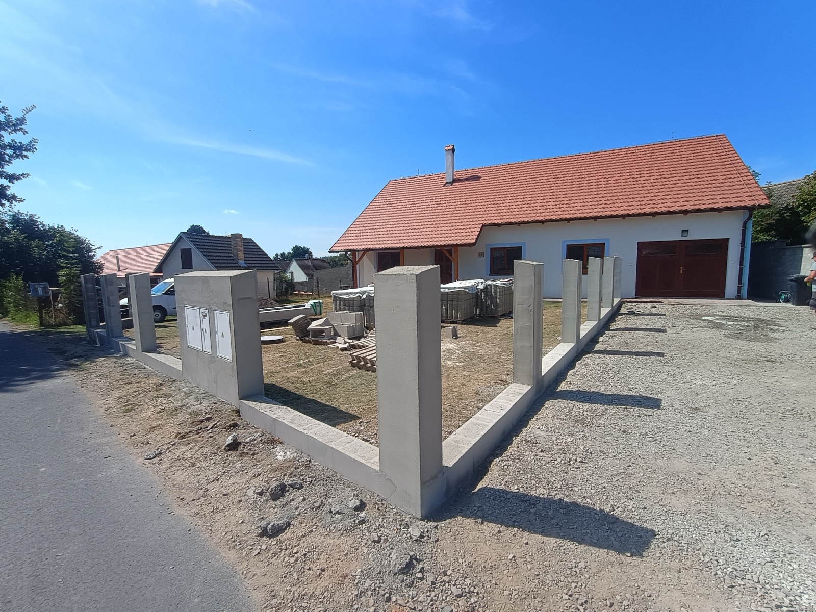 Dokončený bílý rodinný dům s novou fasádou a oplocením
